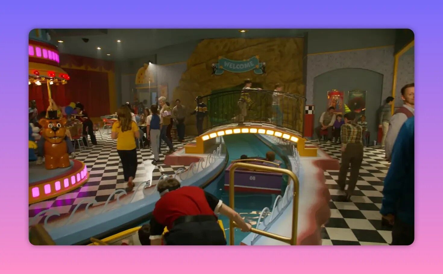 Indoor amusement area with a water flume ride, a small merry-go-round and a checkered floor crowded with visitors
