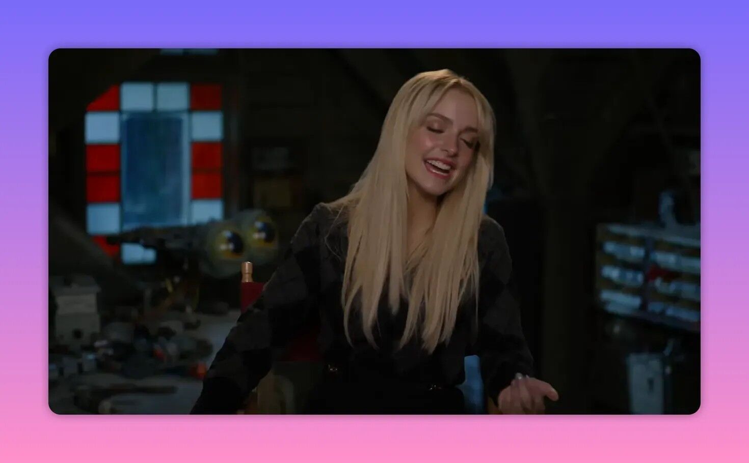 Smiling cast member in a behind-the-scenes interview chair on set